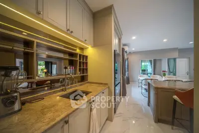 Luxurious open kitchen with marble countertops and modern appliances leading to a spacious living area.
