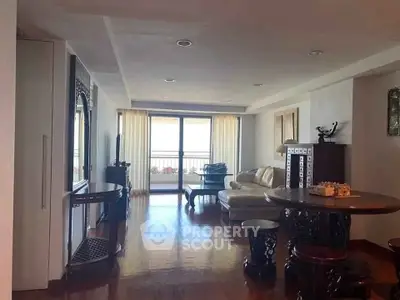 Spacious living room with elegant wooden furniture and large windows leading to a balcony.