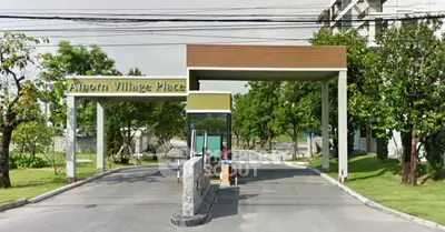 Elegant entrance of Amorn Village Place with modern design and lush greenery.
