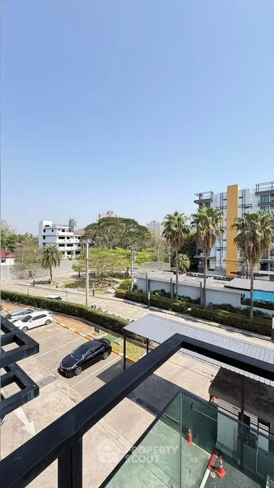 Modern urban view from balcony with lush greenery and contemporary buildings.