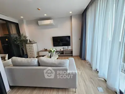 Modern living room with sleek design, featuring a cozy sofa, wall-mounted TV, and large windows for natural light.