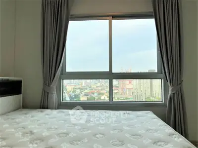 Spacious bedroom with large window offering stunning city view, perfect for urban living.