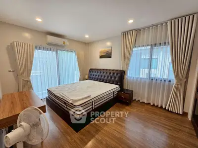 Spacious bedroom with elegant decor and large windows for natural light.