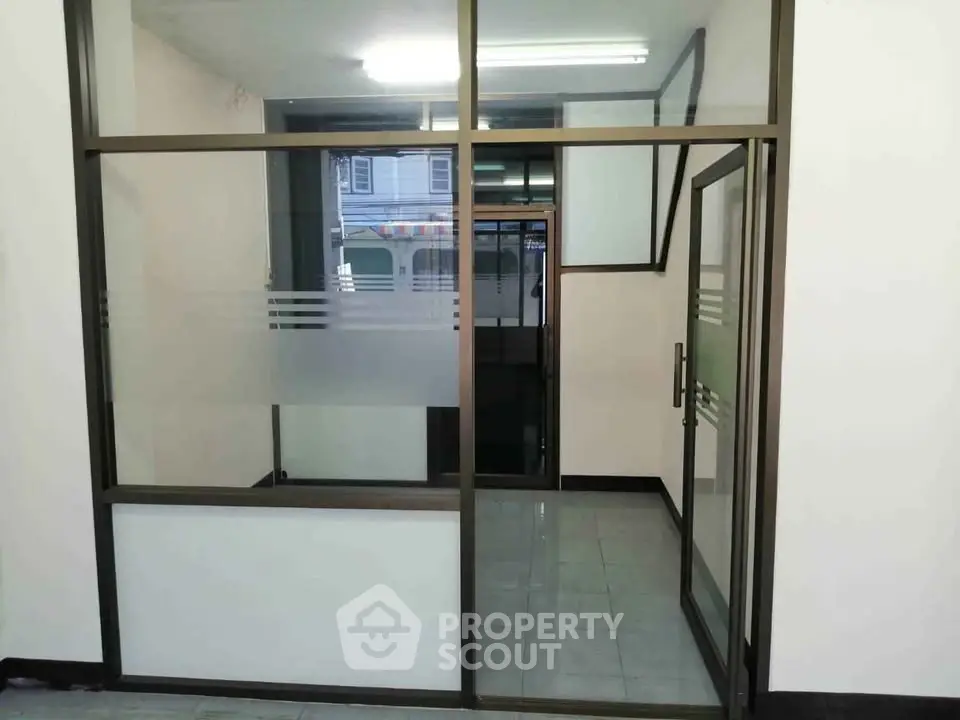 Spacious office entrance with glass partitions and tiled flooring, ideal for professional settings.