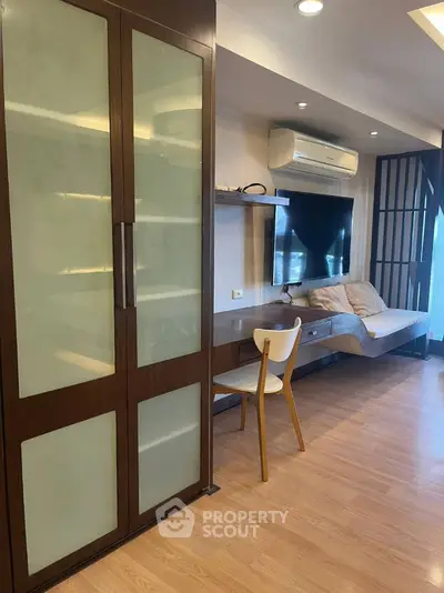 Modern living room with sleek furniture and large TV, featuring a stylish wooden cabinet and cozy seating area.