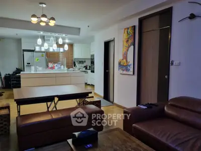 Modern living room with open kitchen, stylish lighting, and cozy leather sofas.