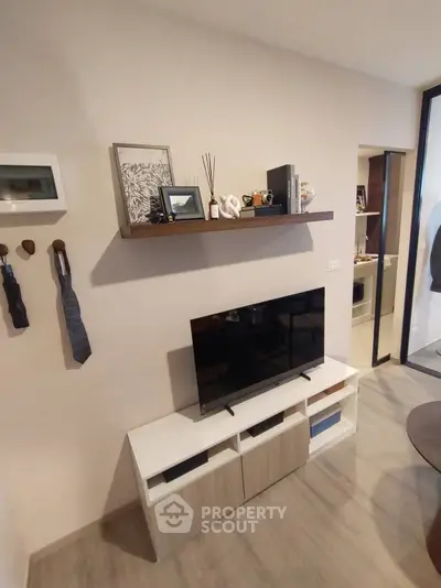 Modern living room with stylish decor and wall-mounted shelf, featuring a sleek TV unit and contemporary design.