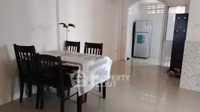 Spacious dining area with modern kitchen and fridge, perfect for family meals.