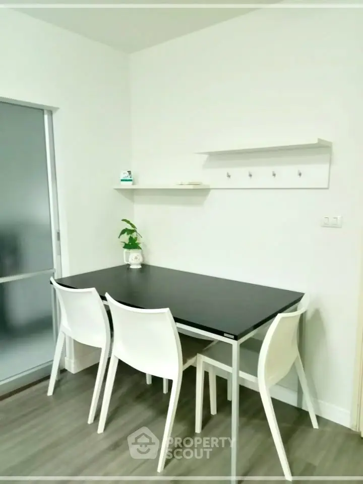 Modern dining area with sleek black table and white chairs in a minimalist setting.