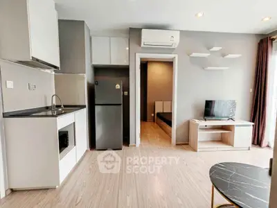 Modern open-plan living room with kitchen and bedroom view, featuring sleek appliances and stylish decor.