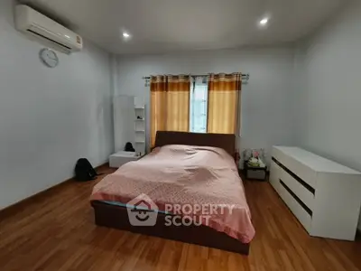 Spacious bedroom with wooden flooring and modern furnishings