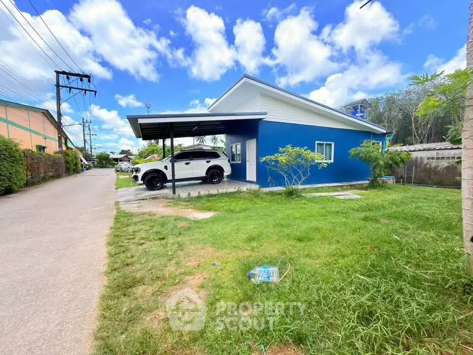 Charming blue single-story house with carport and lush green lawn in a serene neighborhood.