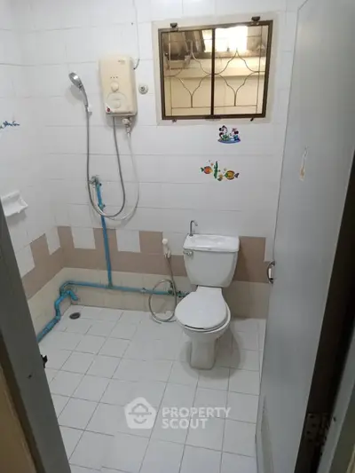 Compact bathroom with shower and toilet in a tiled setting