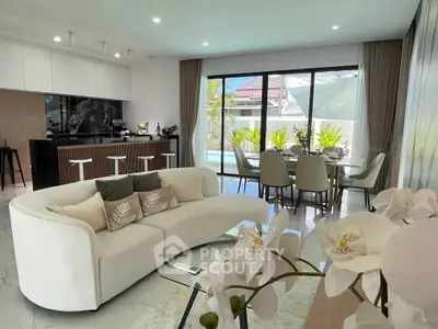 Luxurious open-plan living room with modern kitchen and pool view, perfect for entertaining.