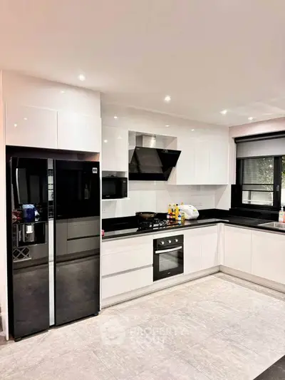 Modern kitchen with sleek white cabinetry, black countertops, and built-in appliances for a stylish cooking space.