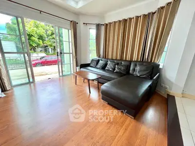 Spacious living room with large windows and stylish leather sofa, offering a bright and inviting atmosphere.