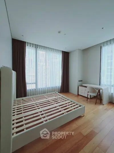 Spacious bedroom with large windows and wooden flooring in modern apartment