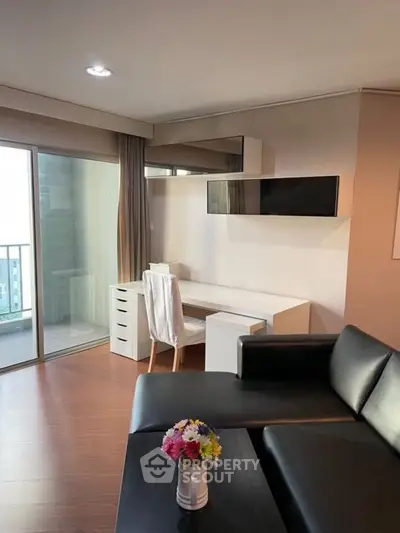 Modern living room with sleek black sofa and balcony view