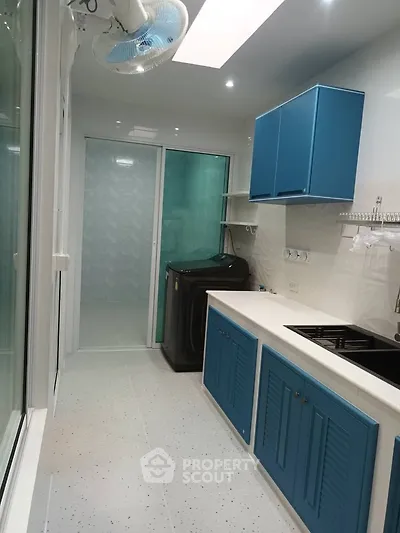 Modern kitchen with blue cabinets and washing machine, sleek design