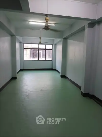 Spacious unfurnished room with large window and ceiling fan, ideal for customization.