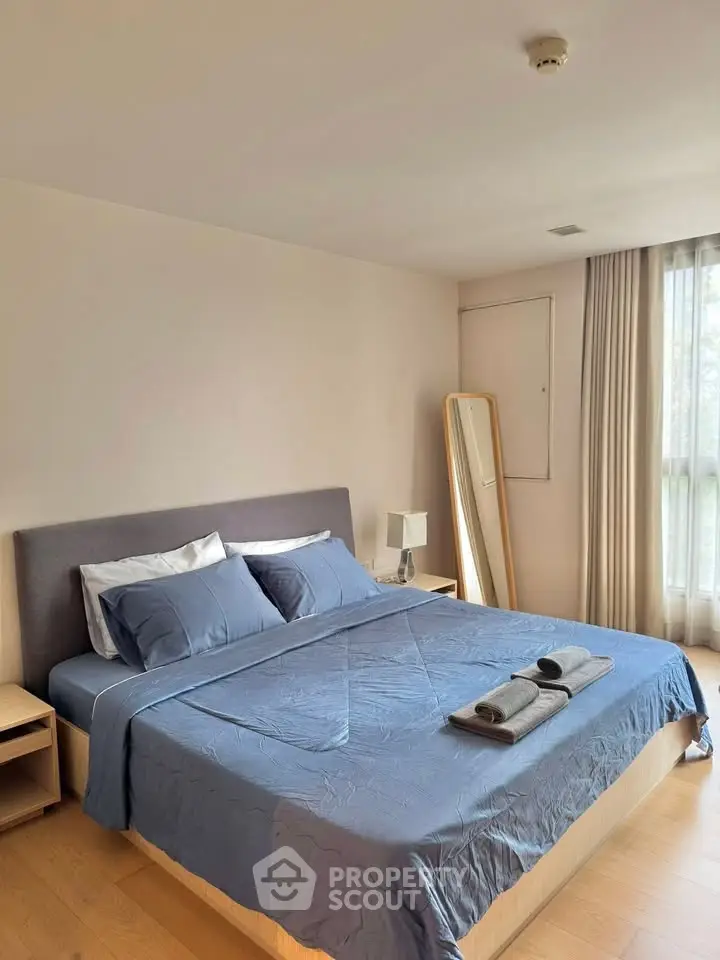 Spacious bedroom with modern decor and natural light, featuring a comfortable bed and stylish furnishings.