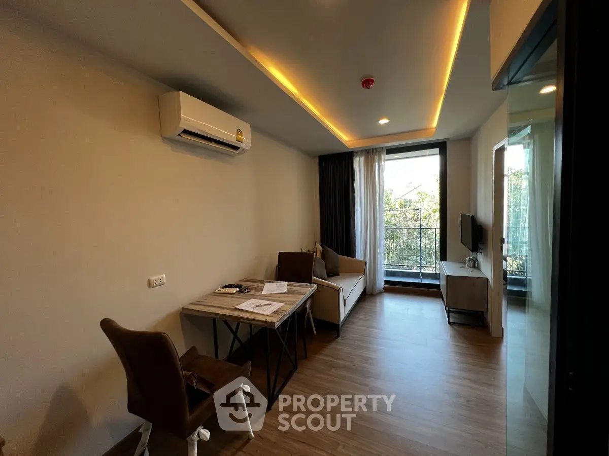 Modern living room with balcony, featuring sleek furniture and ambient lighting.