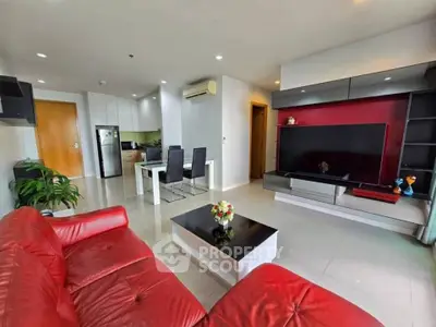 Spacious modern living room with red sofa, sleek TV unit, and open kitchen layout.