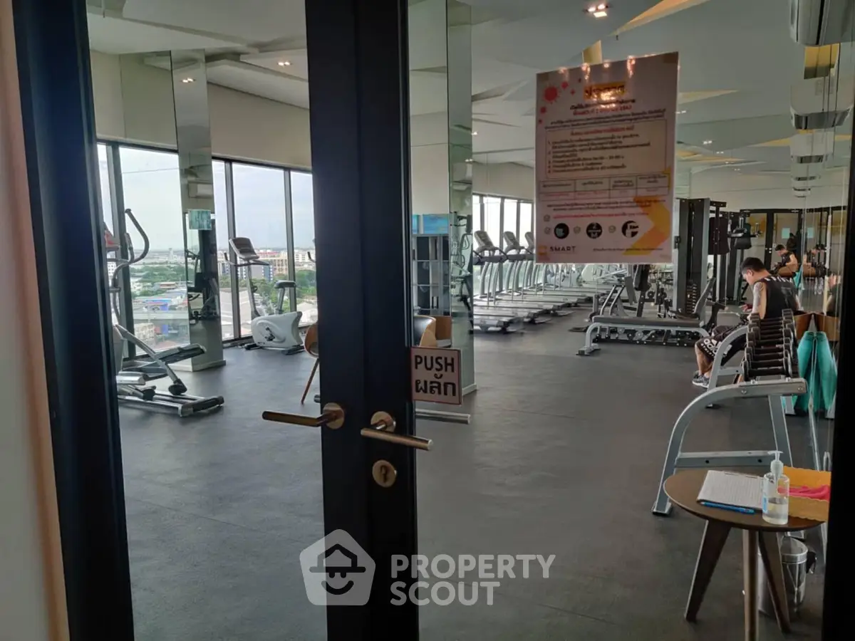 Modern gym with city view, featuring state-of-the-art fitness equipment and sleek design.