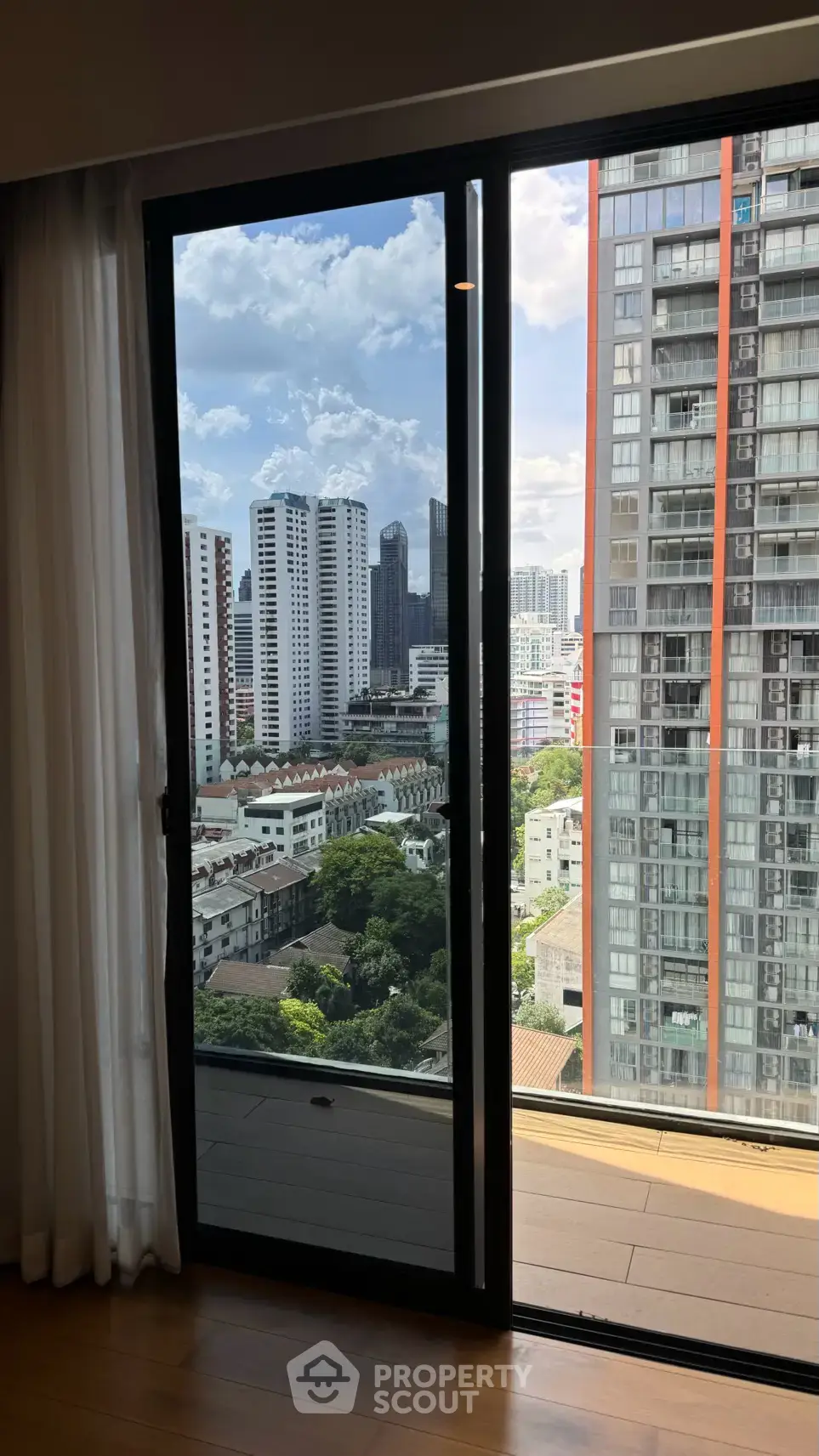 Stunning city view from modern apartment balcony with floor-to-ceiling glass doors.
