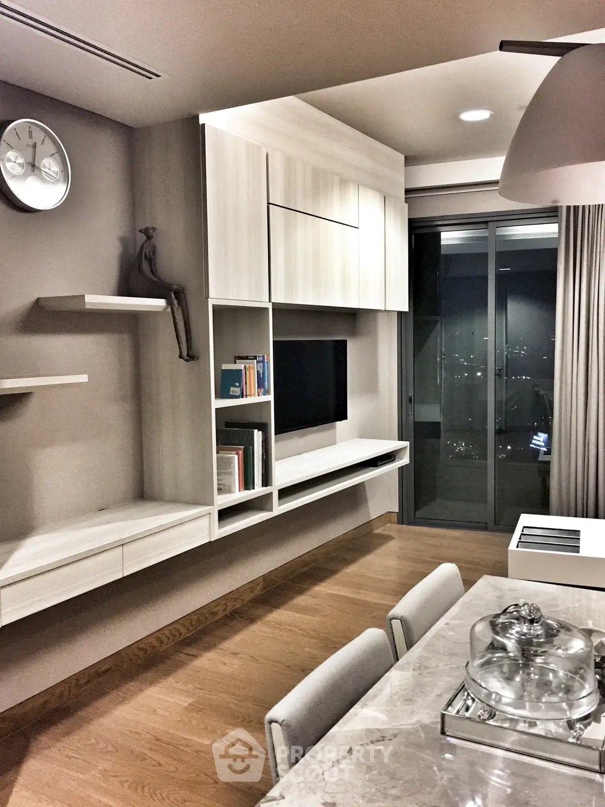 Modern living room with sleek built-in shelves and city view from large window.