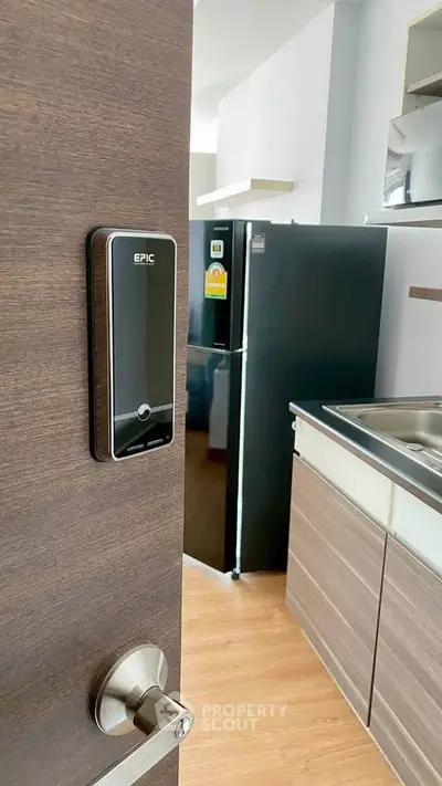 Modern kitchen with sleek appliances and digital door lock for enhanced security.