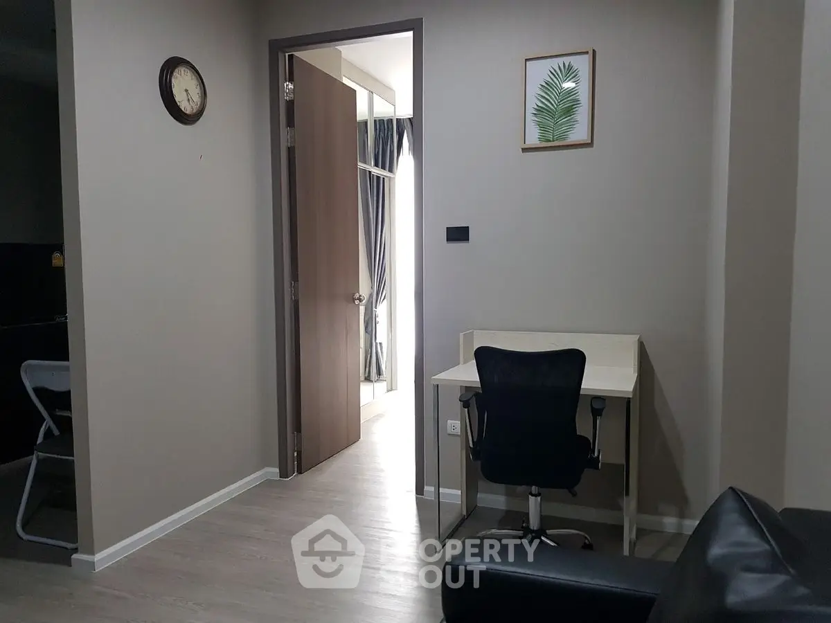 Modern apartment interior with study area and open doorway, showcasing sleek design and neutral tones.