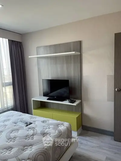 Modern bedroom with stylish TV setup and large window for natural light.