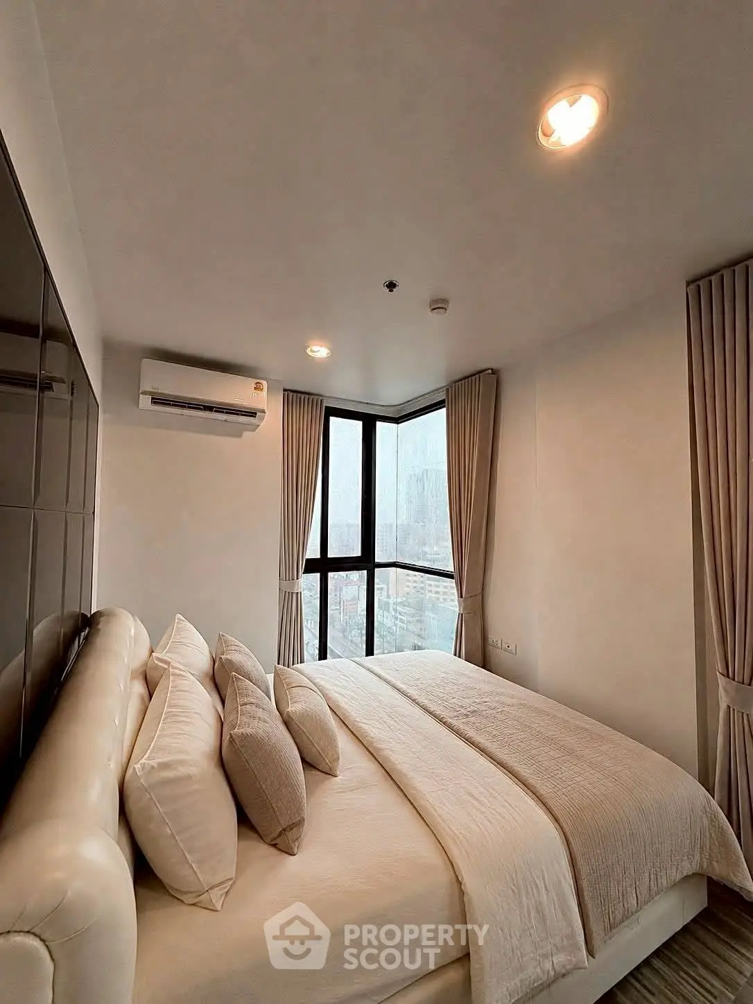 Luxurious bedroom with city view, featuring elegant decor and ample natural light.