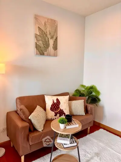 Cozy living room with stylish brown sofa, decorative pillows, and modern artwork, perfect for relaxation.