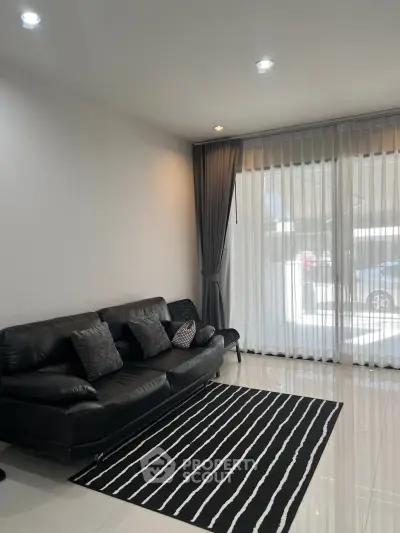 Modern living room with sleek black leather sofa and stylish striped rug