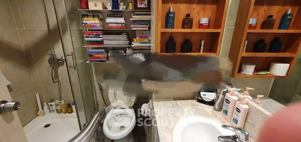 Cozy bathroom with shower, toilet, and ample shelving for storage.