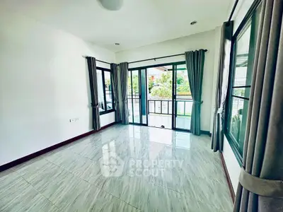 Spacious living room with large windows and balcony access, offering abundant natural light and modern tiled flooring.