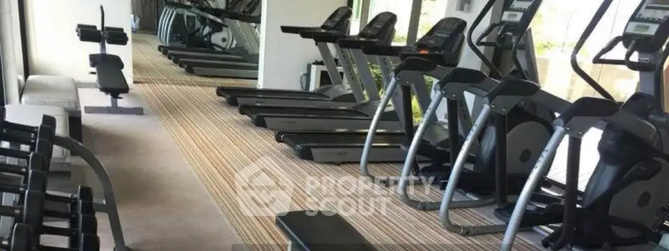 Modern gym with treadmills and weights in luxury apartment complex