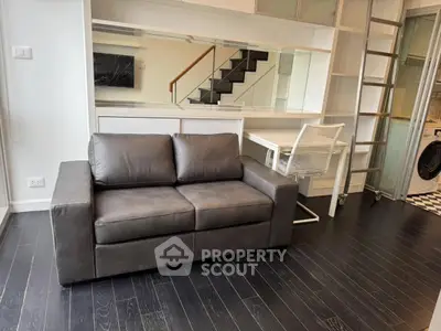 Modern living room with sleek sofa and stylish workspace in a contemporary apartment.