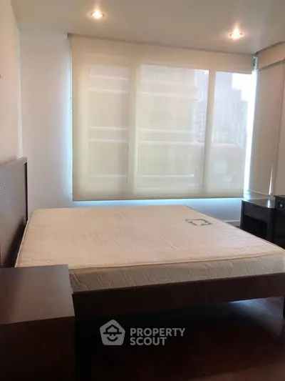 Spacious bedroom with large windows and natural light in modern apartment.
