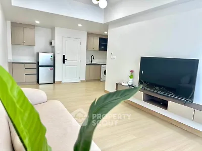 Modern living room with open kitchen, featuring sleek appliances and stylish decor.