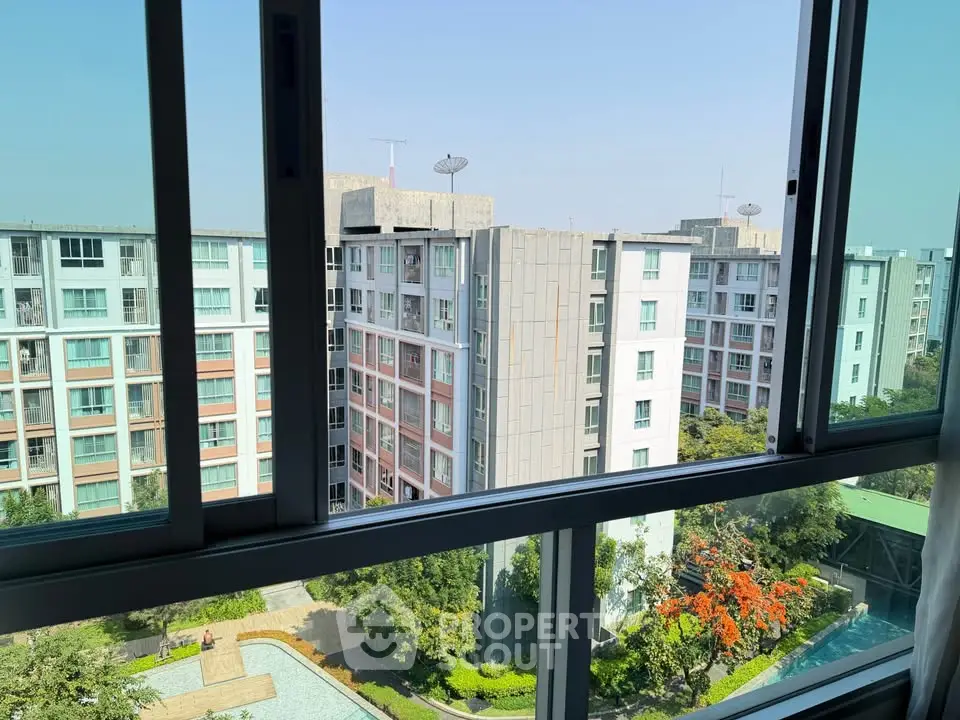 Stunning view from a high-rise apartment window overlooking modern residential buildings and lush greenery.