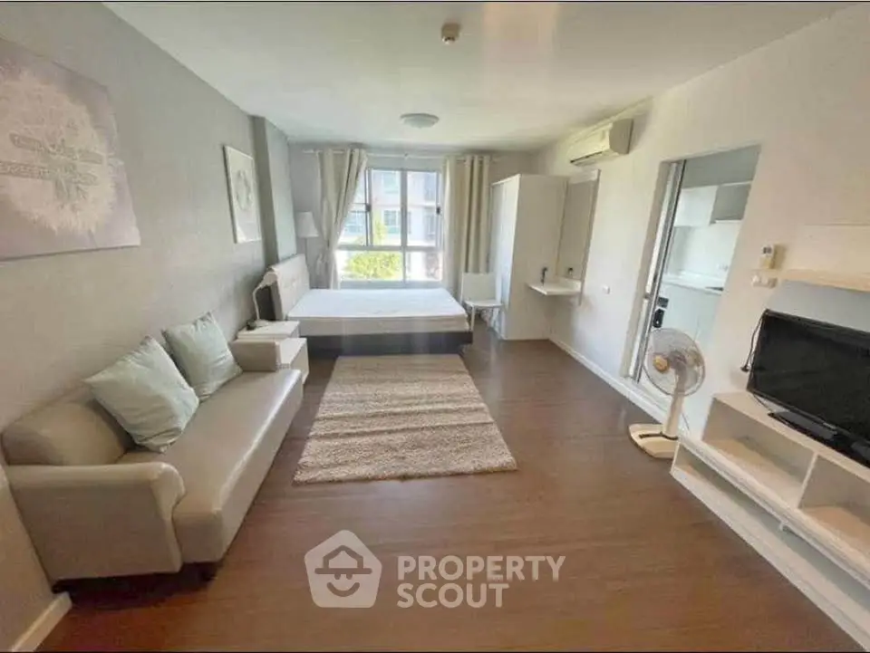 Spacious studio apartment with modern furnishings and large window view.