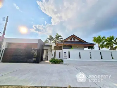 Stunning modern house with spacious driveway and lush palm trees under a bright sky.