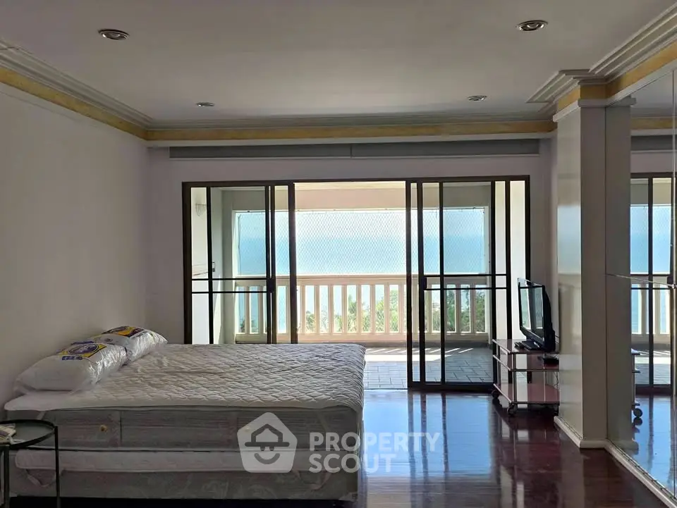 Spacious bedroom with ocean view and balcony access, perfect for serene living.