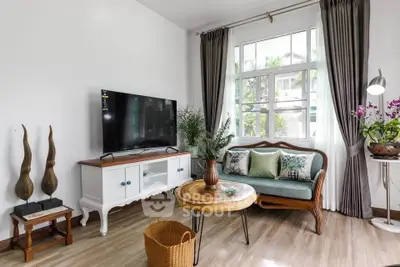 Charming living room with stylish decor and natural light, featuring a cozy sofa and modern TV setup.