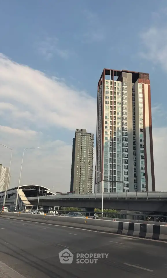 Modern high-rise building with urban skyline and clear blue sky, showcasing contemporary architecture.