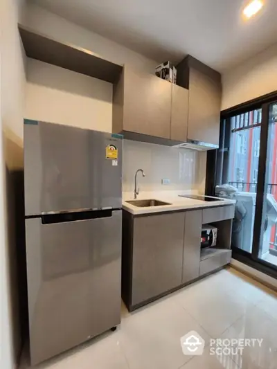 Modern compact kitchen with sleek cabinets and stainless steel fridge in urban apartment