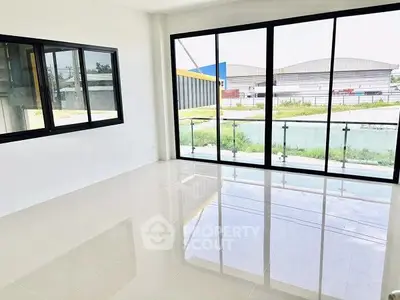 Spacious modern room with large windows and glossy floors, offering a bright and airy atmosphere.